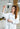 Person in a lab coat holding a beaker with safety goggles on, in a laboratory setting.